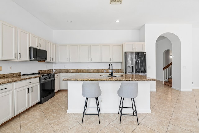 kitchen with electric range, sink, refrigerator with ice dispenser, and a kitchen island with sink