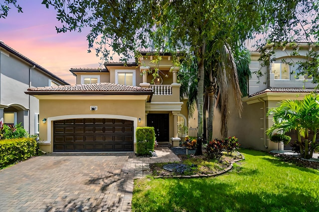 mediterranean / spanish-style home featuring a balcony, a garage, and a lawn