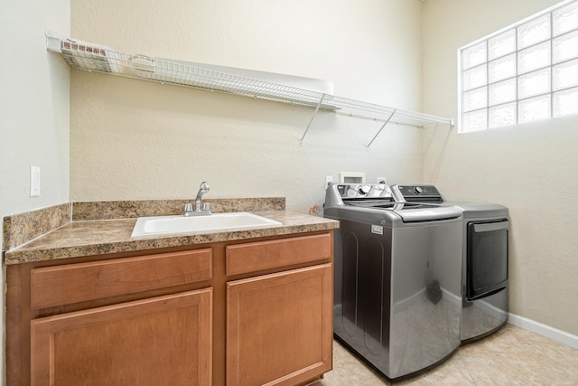 laundry area with light tile patterned flooring, sink, separate washer and dryer, and cabinets