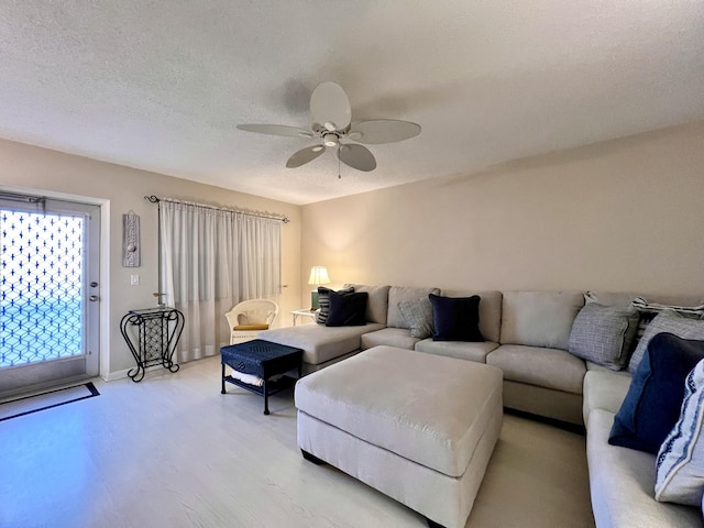 living room featuring ceiling fan, a textured ceiling, and light wood-type flooring