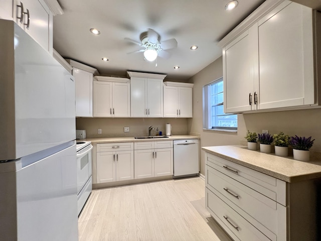 kitchen featuring white appliances, white cabinetry, sink, light wood-type flooring, and ceiling fan