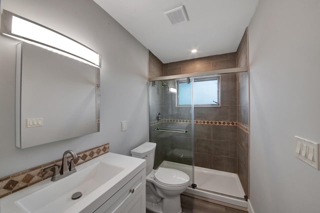 bathroom featuring hardwood / wood-style floors, vanity, toilet, and a shower with shower door