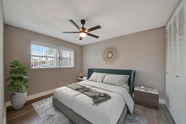 bedroom with ceiling fan, wood-type flooring, and a textured ceiling