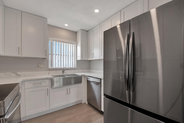 kitchen with light stone countertops, sink, white cabinets, and stainless steel appliances