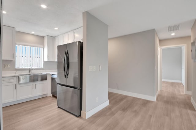 kitchen featuring white cabinetry, sink, light hardwood / wood-style flooring, and appliances with stainless steel finishes