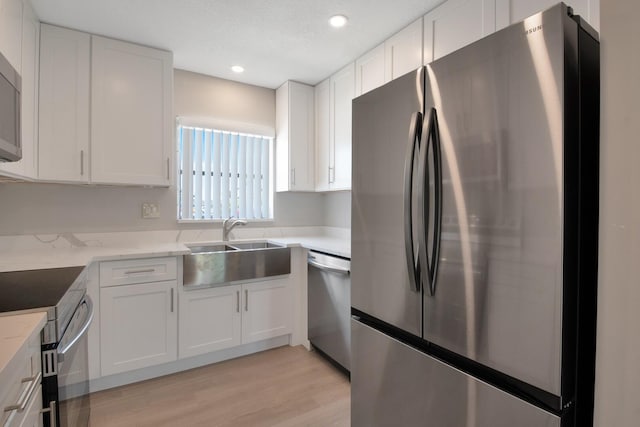 kitchen with white cabinetry, light hardwood / wood-style floors, light stone counters, and appliances with stainless steel finishes