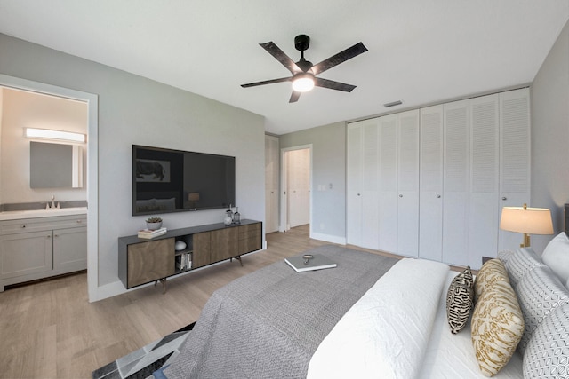 bedroom featuring ensuite bathroom, sink, light hardwood / wood-style flooring, ceiling fan, and a closet