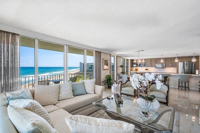 living room featuring a water view, a textured ceiling, and a chandelier