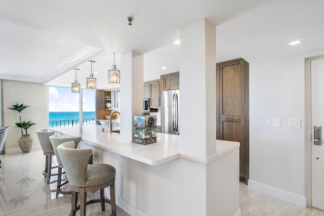 kitchen with stainless steel fridge, sink, decorative light fixtures, a water view, and a wall of windows