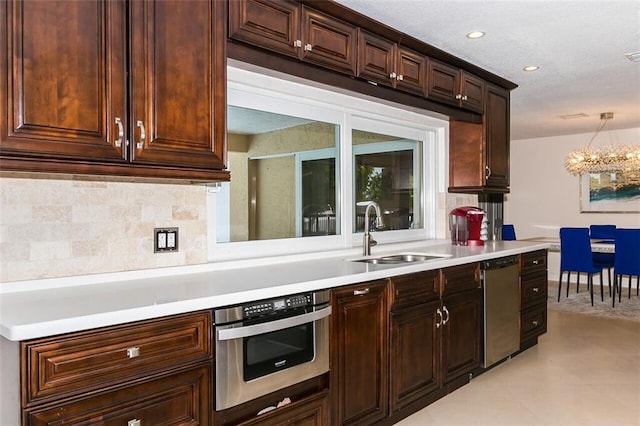 kitchen with appliances with stainless steel finishes, sink, hanging light fixtures, a notable chandelier, and decorative backsplash