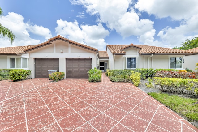 view of front of property with a garage, concrete driveway, a tiled roof, and stucco siding