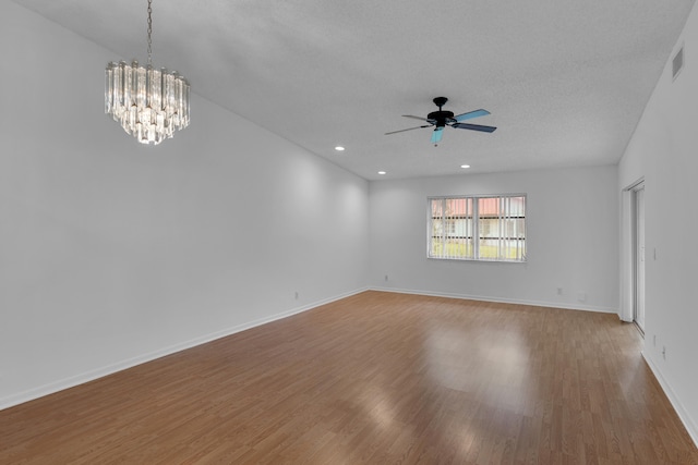 spare room featuring a textured ceiling, ceiling fan with notable chandelier, and wood-type flooring