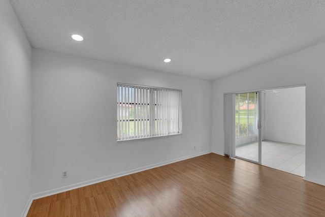 spare room with lofted ceiling, light hardwood / wood-style flooring, and a wealth of natural light