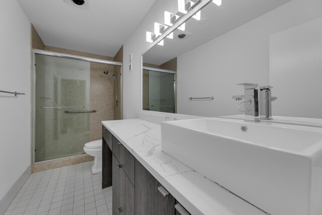 bathroom featuring tile patterned flooring, a shower with door, toilet, and vanity