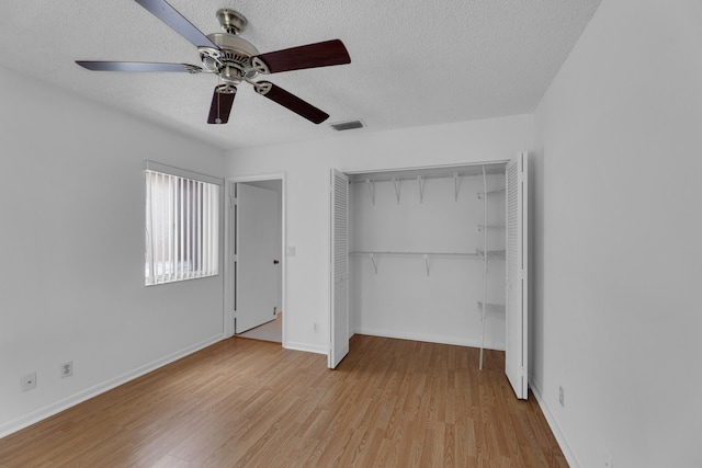 unfurnished bedroom with a textured ceiling, a closet, light wood-type flooring, and ceiling fan