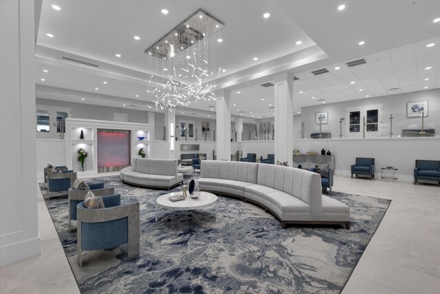 living room with light tile patterned floors, decorative columns, and a tray ceiling