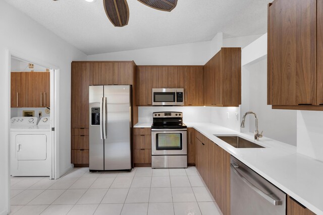 kitchen with light tile patterned flooring, ceiling fan, stainless steel appliances, sink, and washing machine and clothes dryer