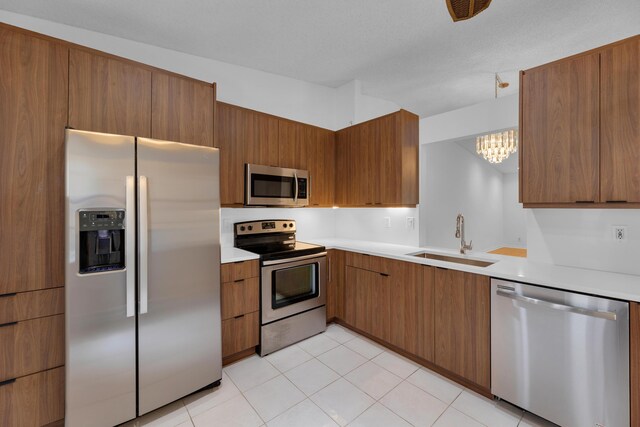 kitchen featuring light tile patterned flooring, stainless steel appliances, sink, and an inviting chandelier