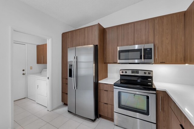 kitchen featuring washing machine and dryer, appliances with stainless steel finishes, and light tile patterned floors