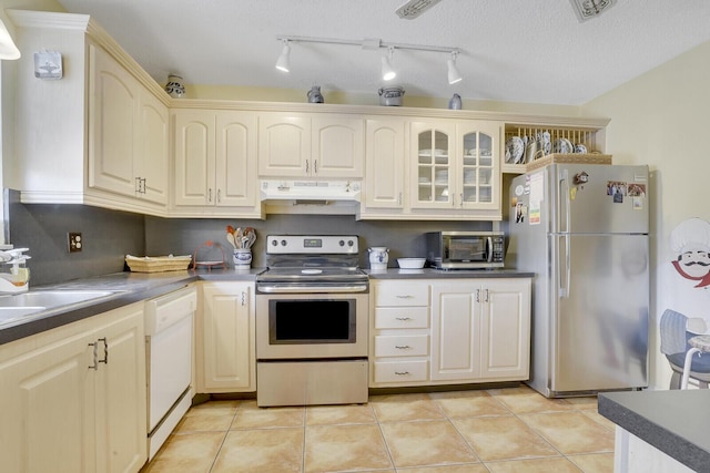 kitchen featuring cream cabinetry, stainless steel appliances, a textured ceiling, and light tile patterned floors