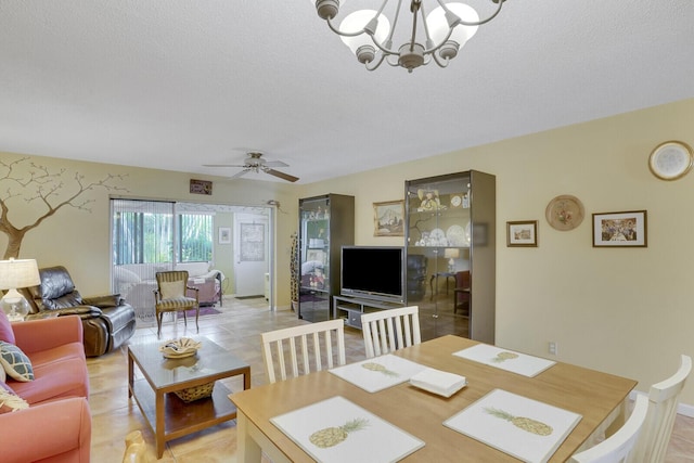 tiled dining area with ceiling fan with notable chandelier and a textured ceiling