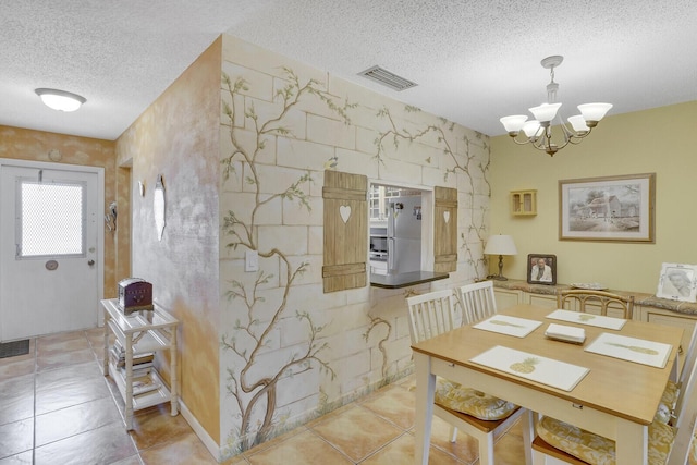 dining room featuring a chandelier, a textured ceiling, and light tile patterned floors