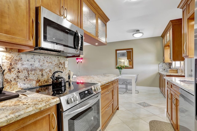 kitchen featuring light stone counters, stainless steel appliances, light tile patterned floors, and decorative backsplash