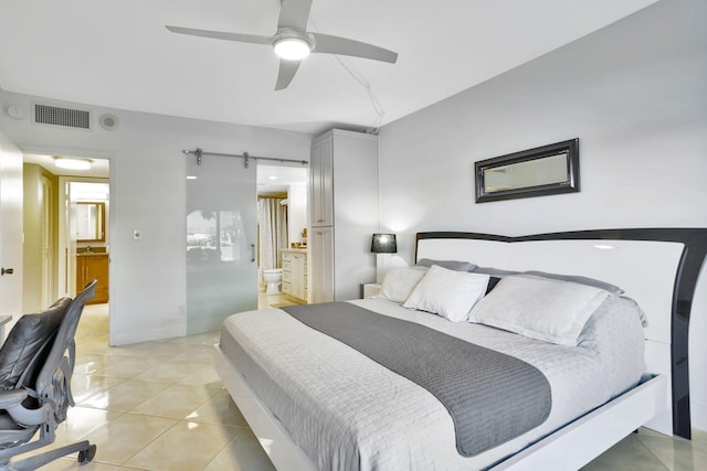 bedroom featuring ensuite bathroom, ceiling fan, a barn door, and light tile patterned floors