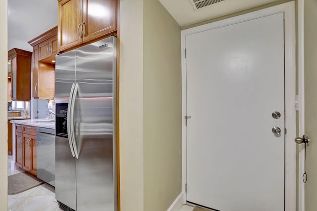 kitchen with light stone countertops, appliances with stainless steel finishes, and light tile patterned floors