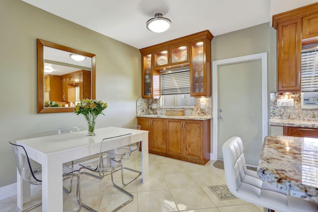 kitchen featuring decorative backsplash, light stone countertops, and light tile patterned floors