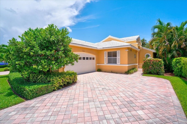 view of front of house featuring an attached garage, decorative driveway, and stucco siding