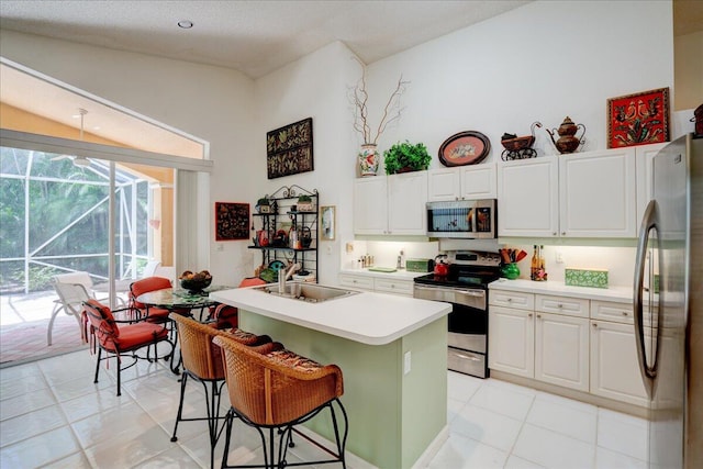 kitchen featuring appliances with stainless steel finishes, white cabinets, sink, light tile patterned floors, and lofted ceiling