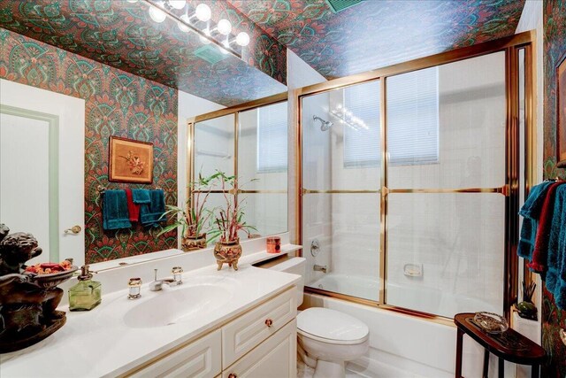 full bathroom featuring toilet, shower / bath combination with glass door, and vanity