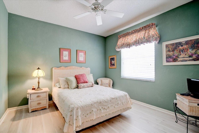 bedroom featuring light hardwood / wood-style flooring, a textured ceiling, and ceiling fan