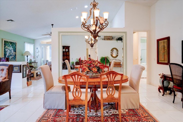 tiled dining space featuring ceiling fan with notable chandelier and high vaulted ceiling