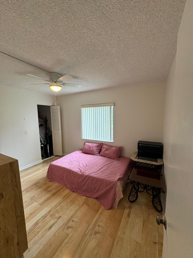 bedroom featuring ceiling fan, a textured ceiling, and light hardwood / wood-style flooring