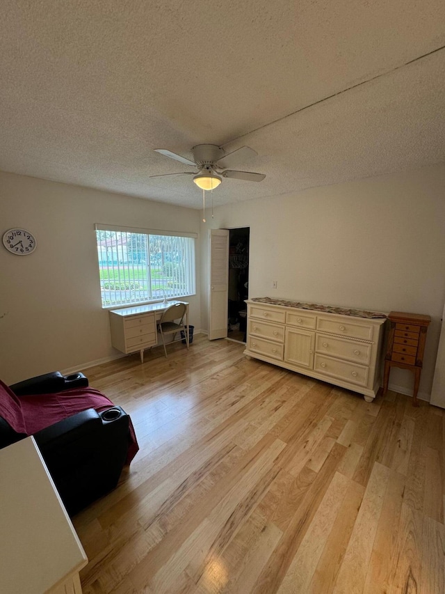 interior space with ceiling fan, a textured ceiling, and light hardwood / wood-style floors