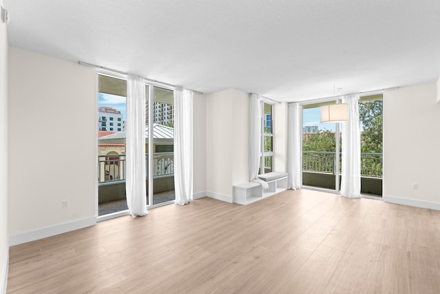 unfurnished living room featuring light hardwood / wood-style flooring, a textured ceiling, plenty of natural light, and expansive windows