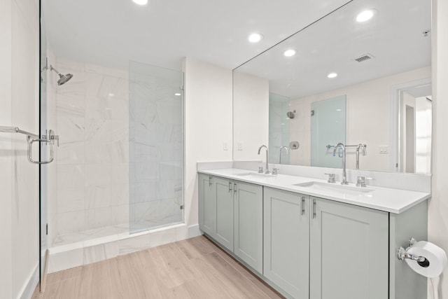 bathroom featuring dual vanity, a tile shower, and wood-type flooring