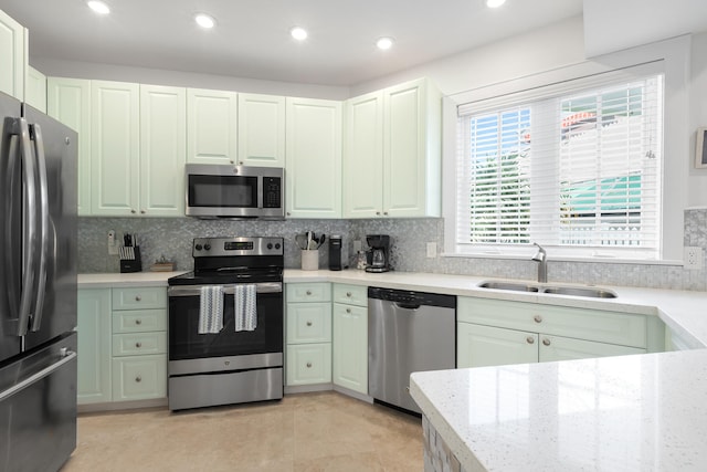 kitchen with backsplash, green cabinetry, light tile patterned floors, sink, and stainless steel appliances