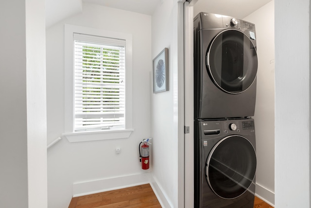 clothes washing area featuring stacked washer and clothes dryer and wood-type flooring