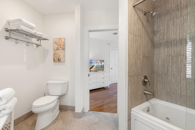 bathroom with toilet, washtub / shower combination, and hardwood / wood-style flooring