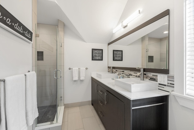 bathroom with decorative backsplash, tile patterned flooring, double vanity, vaulted ceiling, and walk in shower