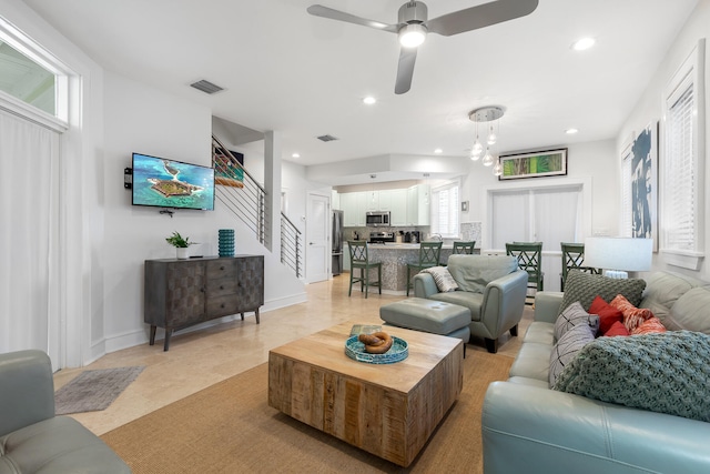 living room featuring a wealth of natural light, ceiling fan with notable chandelier, and light tile patterned floors