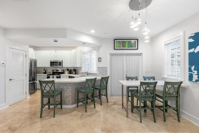 kitchen with tasteful backsplash, plenty of natural light, white cabinetry, and stainless steel appliances