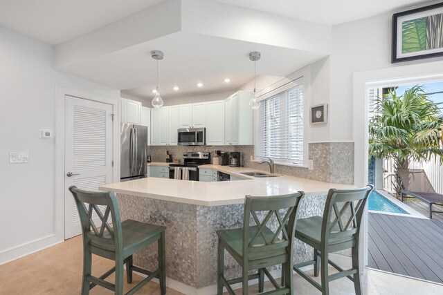 kitchen featuring stainless steel appliances, sink, pendant lighting, light tile patterned floors, and a breakfast bar