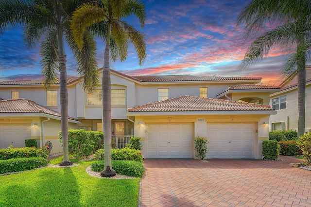 7869 Laina Ln Unit 2, Boynton Beach, FL 33437 - view of front of home featuring a garage, stucco siding, decorative driveway, a tile roof, and a front lawn