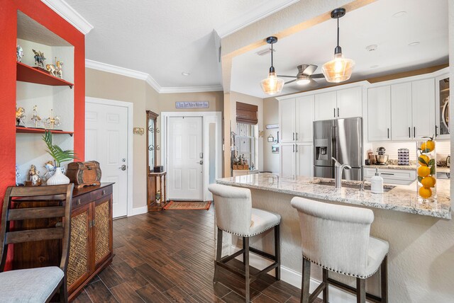 7869 Laina Ln Unit 2, Boynton Beach, FL 33437 - kitchen with stainless steel fridge with ice dispenser, white cabinetry, a kitchen bar, light stone countertops, and crown molding