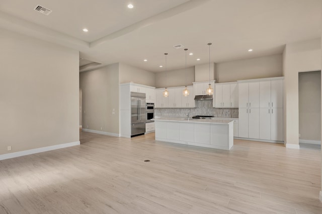 kitchen featuring a kitchen island with sink, sink, hanging light fixtures, light wood-type flooring, and white cabinetry