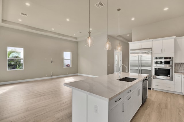 kitchen featuring white cabinets, a healthy amount of sunlight, sink, and an island with sink